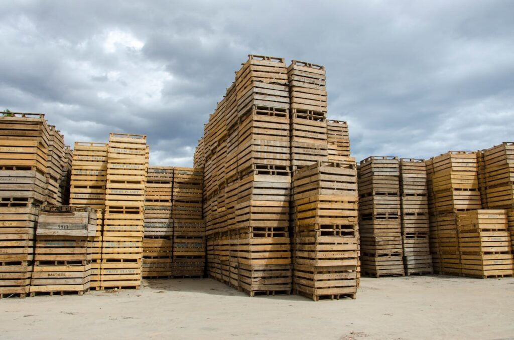 High stack of wooden crates outdoors under a cloudy sky, showcasing industrial storage.